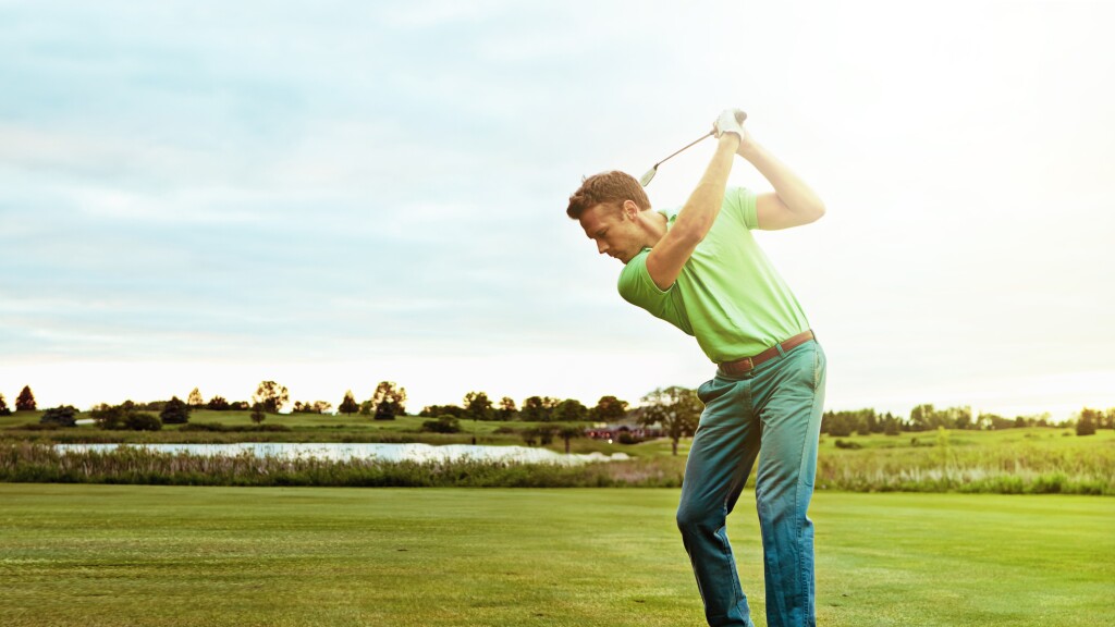 Golfer taking a swing on golf course 
